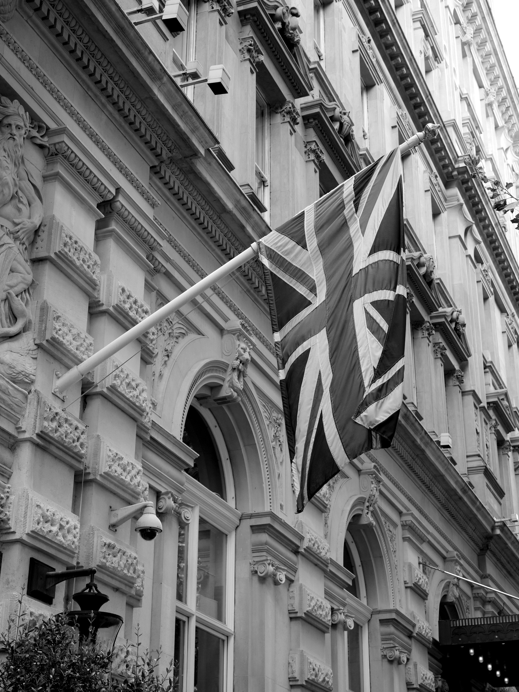 A Union Jack flag hanging from an ornate carved-stone building facade.